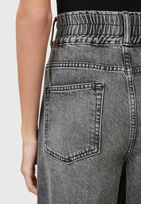 Hoge taille zwarte denim broek met een gestructureerde tailleband, voorzien van een enkele achterzak en contrasterende stiksel-details.