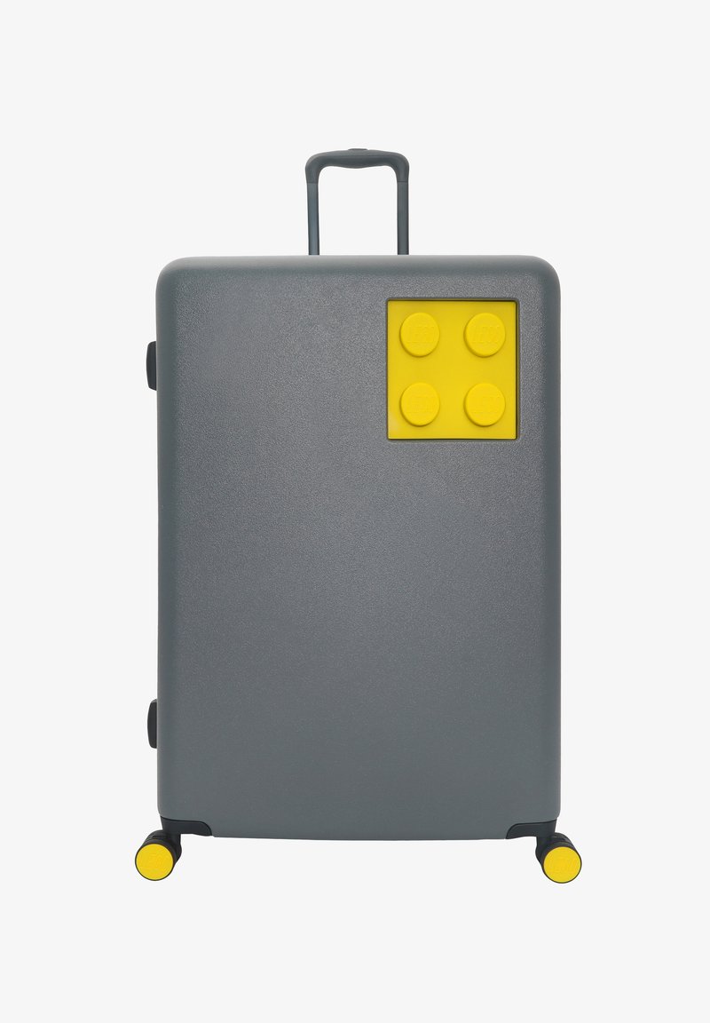Gray suitcase with a textured finish, featuring a yellow LEGO-style accent on one side and yellow wheels for mobility.
