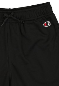 Pantalones cortos deportivos negros hechos de un tejido de malla transpirable, con una cintura elástica y un cordón. Presenta un pequeño logo bordado.