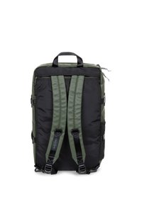 Mochila de tela negra y verde oliva con correas acolchadas ajustables, una asa superior para llevar y un bolsillo delantero con cremallera. Cuenta con bolsillos laterales de malla.
