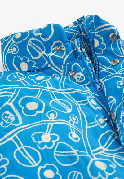 Veste bleue avec motif floral blanc, dotée d'une fermeture éclair et de boutons-pression métalliques au col et à l'avant.