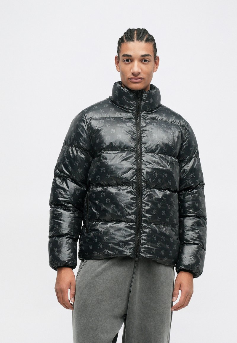 Schwarze Pufferjacke mit hohem Kragen, glänzender Oberfläche und subtilen Logomuster. Der Reißverschluss vorne sorgt für einen sicheren Verschluss.