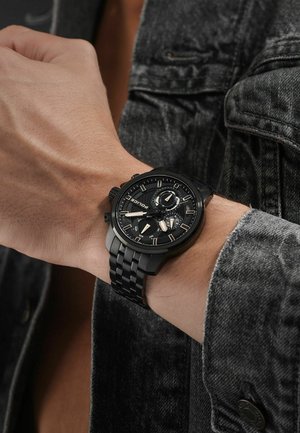 Orologio analogico nero con quadrante strutturato, dettagli metallici e bracciale a maglie. Presenta tre sotto-quadranti e una cassa robusta.