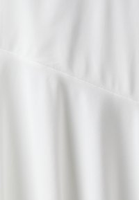 Tăblia albă din material textil cu o textură netedă și linii subtile de pliere, împărțită în secțiuni cu o cusătură ușor în unghi. Fără modele sau accente vizibile.