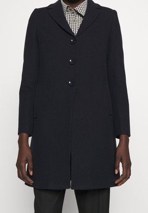 Navy wool coat with a notched collar, five buttons, and side pockets. Features a tailored fit and smooth texture. Gingham shirt is visible underneath.
