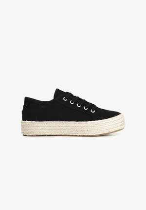 Zapatilla de lona negra con punta redonda, suela de goma y mediado de esparto tipo yute natural. Cuenta con seis ojales y cordones negros.