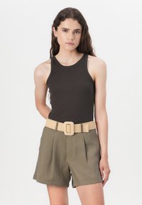 Hnědý žebrovaný tank top v kombinaci s olivově zelenými šortkami s vysokým pasem. Šortky mají texturovaný béžový opasek s velkou čtvercovou sponou.