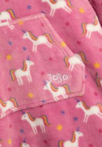 Rosa fleece stof med gentagne hvide enhjørninger med regnbuefarvede maner og stjerner. Inkluderer en lomme med broderet navn "Jojo."