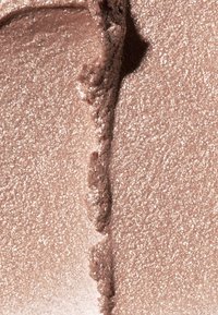 Metallisk roseguldcreme med en glat, blank overflade; har fin glitter og en let uregelmæssig påføringsflade.