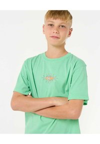 Camiseta de algodón en verde menta con un gráfico circular en naranja y blanco en el centro, de manga corta y con un corte relajado.