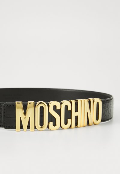 Must mustrahm on mustrustis mustkulgaste kuldne "MOSCHINO" logo, mis näitab siledat tekstuuri ja julget kirja.