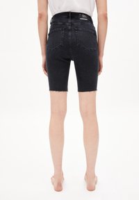 Pantalones cortos de mezclilla negra con dobladillo deshilachado, diseño de cinco bolsillos, cintura alta y sutiles detalles de costura en la parte trasera. Estilo casual.