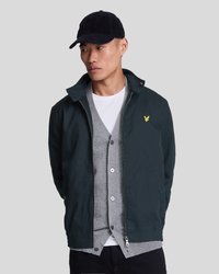 Căciulă din velur naval, jachetă verde închis cu guler și fermoare, cardigan gri cu nasturi, cămașă albă dedesubt, pantaloni negri.