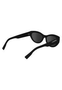 Black cat-eye sunglasses with dark lenses, featuring a smooth plastic frame and slender arms. Lacoste logo on the side.