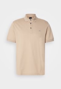 Polo beige à manches courtes avec patte de boutonnage à trois boutons et petit logo brodé sur le côté gauche de la poitrine.