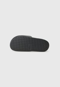 Black sandal sole featuring a textured pattern with small squares, a logo imprint, and flat edges for grip and stability.