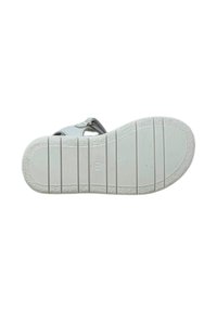 Sole di sandalo bianca con gomma testurizzata, scanalature orizzontali e motivo circolare vicino al tallone. Hardware della cinturino regolabile visibile.
