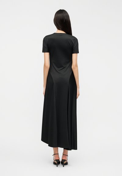 Μαύρο φόρεμα μήκους έως το πάτωμα με κοντά μανίκια, κατασκευασμένο από απαλό ύφασμα. Διαθέτει εφαρμοστό μπούστο και ρέουσα φούστα. Μίνιμαλ σχεδιασμός.