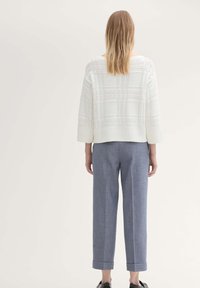 Witte, getextureerde gebreide trui met driekwartmouwen, gecombineerd met blauwe, op maat gemaakte, opgerolde broek. Effen kleur, relaxte pasvorm, minimaal ontwerp.