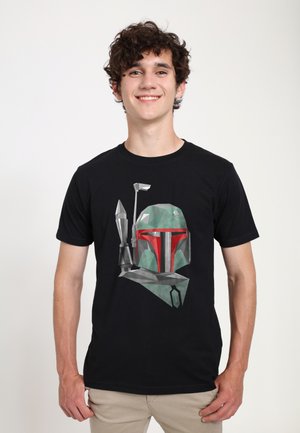 Sort t-shirt med et polygonalt design af en hjelm med grønne og røde accenter, ledsaget af en grafik af et våben.