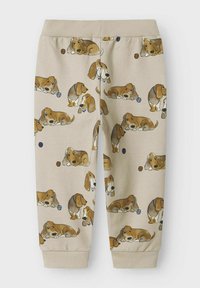 Beige sweatpants met een herhaald cartoonpatroon van bruine honden. Zacht materiaal met een geribde tailleband en enkelsokken.