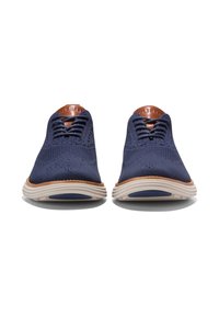 Navy pletené boty s texturovaným svrškem, světle hnědé detaily na jazyku a lehkou krémovou podrážkou s modrými akcenty.