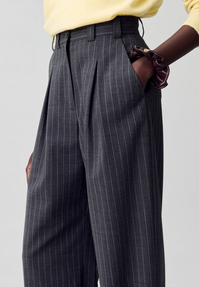 Pantalones de rayas gris con frente plisado, cinturilla alta y bolsillos laterales. Presenta una textura suave y un corte entallado.