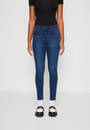 Jeans subțiri din denim albastru, cu talie medie, design cu cinci buzunare și o cusătură subtilă. Asortați cu pantofi cu platformă negri și albi.