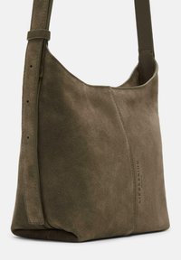 Zielono-oliwkowa torebka na ramię z zamszu, o miękkiej fakturze, minimalistycznym designie i regulowanym pasku; z wytłoczonym logo po jednej stronie.