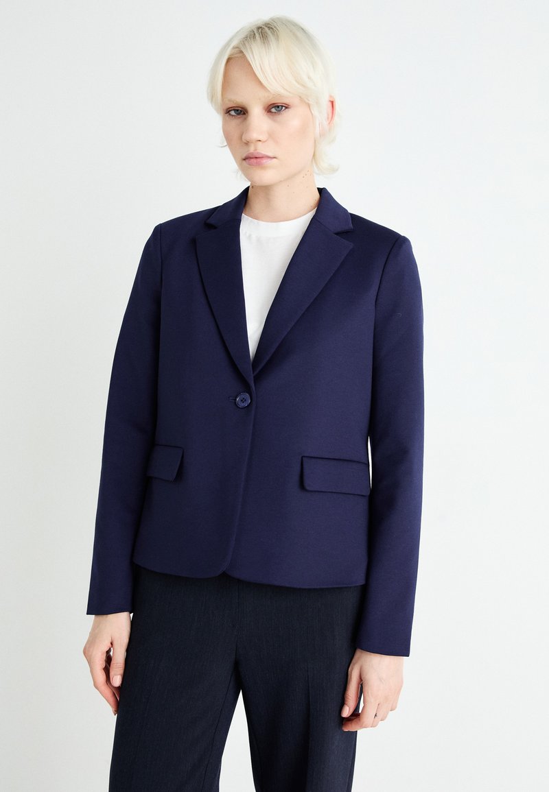 Blazer sartoriale navy in tessuto elasticizzato, presenta una chiusura con un bottone, due tasche frontali, rever a falda e un design slim fit.