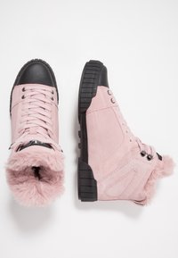 Botas de tobillo de ante rosa con punteras de goma negra, con forro rosa esponjoso, cordones redondos y suelas negras texturizadas.