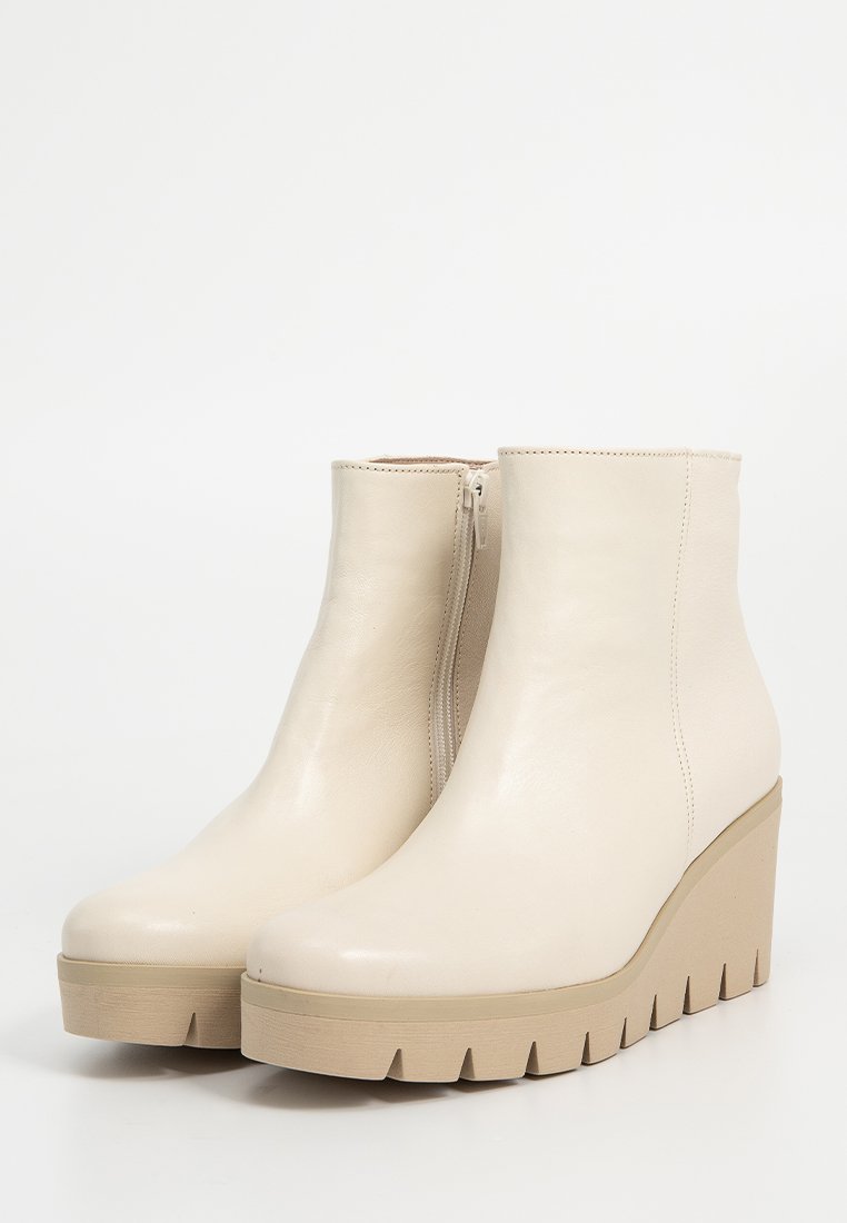 Beige enkelbotten met een glanzend leren bovendeel, zijrits en een chunky platform-wedge zool met een getand rand.