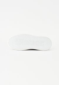 Fehér gumitalpú sneaker hullámos mintázattal, lekerekített orral és sima felülettel, a tapadás és tartósság érdekében tervezve.