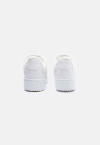 Baskets blanches avec des accents en fausse fourrure texturée au niveau du talon. Semelle plate-forme surélevée avec logo en relief à l'arrière. Tige en cuir lisse.