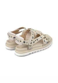 Beige sandalen met meerdere banden, versierd met ronde zilveren studs. Dikke witte zool en zachte textuur, ontworpen voor comfort en ondersteuning.