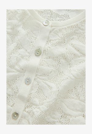 Balts adīts kardigans ar teksturētu atvērto rakstu un četriem pērlīšu pogām priekšpusē. Mīksts, smalks audums.