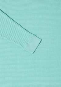 Jasny turkusowy, długi rękaw, koszula z prążkowaną teksturą oraz detalami mankietów. Materiał wydaje się miękki i gładki.