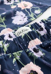 Tissu en coton floral bleu marine avec des fleurs roses, lavande et noires. Doté d'un élastique froncé à la taille et d'une étiquette blanche avec "Cath Kidston."