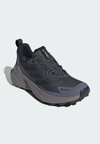 Černá turistická bota s prodyšným svrškem z meshu a pevným textilním překrytím, texturovanou mezipodešví a robustní podešví s gripovými vzory. Viditelné logo GORE-TEX.