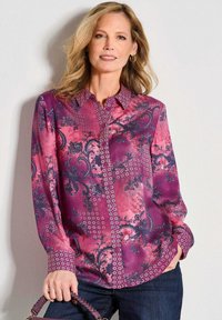 Langarm, knoopsluiting overhemd in tinten van roze en paars met paisley- en diamantpatronen. De stof heeft een gladde, glanzende afwerking.