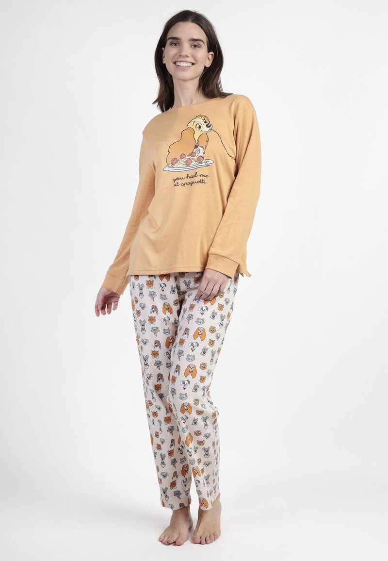 Conjunto de pijama de dos piezas. Parte superior de manga larga en mostaza con gráfico de perro de dibujos animados y texto. Pantalones crema estampados con diversas ilustraciones de animales.