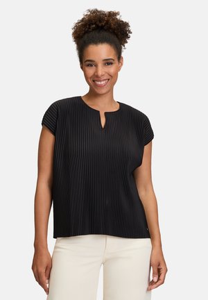 Haut plissé noir avec un col rond et des manches courtes, présentant un détail en trou de serrure. Texture lisse, associé à un pantalon de couleur claire.