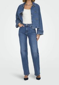 Džínová bunda volného střihu, modré barvy, se zlatými knoflíky. V kombinaci s vysokými modrými džíny. Hladká textura a ohrnuté rukávy.