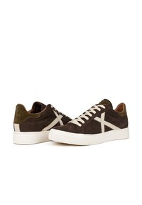 Sneakers in suede marrone scuro con lacci bianchi, caratterizzati da un motivo di design sulla parte superiore e una suola in gomma bianca; stile casual.