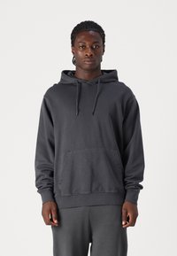 Dunkelgrauer Kapuzenpullover aus weichem Material mit einer Kängurutasche vorne und gerippten Bündchen. Minimalistisches Design mit bequemer Passform.