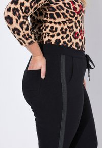Zwarte joggers met een gestructureerde afwerking, voorzien van zijzakken en een contrasterende denimachtige streep langs de buitenkant van het been. Met een gestrikt koord in de taille.