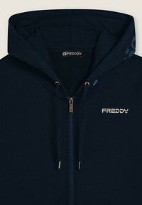 Felpa con zip di colore blu navy, con cappuccio, cordini, zip in metallo e logo "FREDDY" bianco sul petto e sull'etichetta interna.