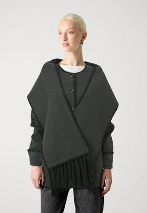 Dunkelgrauer Poncho mit Fransen, der ein dreieckiges Design und Zickzackbesatz aufweist. Beinhaltet vordere Knöpfe und leicht lockere Ärmel.