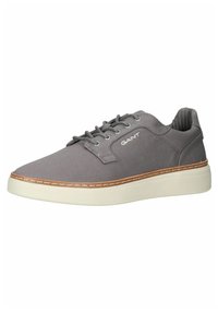 Gray canvas sneaker with white rubber sole, round toe, and lace-up design. Features subtle branding and stitched accents along the sole.