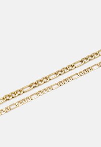 Colares de corrente de metal dourado, um com elos alongados e o outro com elos curtos e redondos, exibidos sobre um fundo branco.